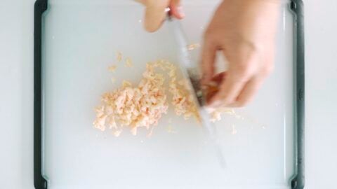 Chopping chicken skin to make chicharron for Arroz Caldo