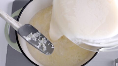 Adding chicken stock to Arroz Caldo.