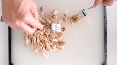 Shredding chicken with two forks.