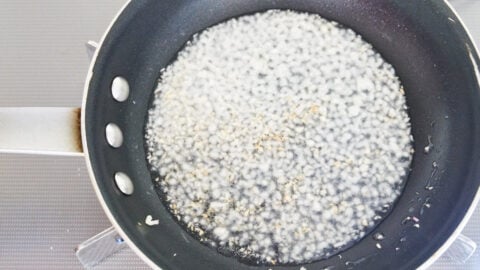 Garlic and ginger frying in a pan to make chili oil for bang bang chicken.