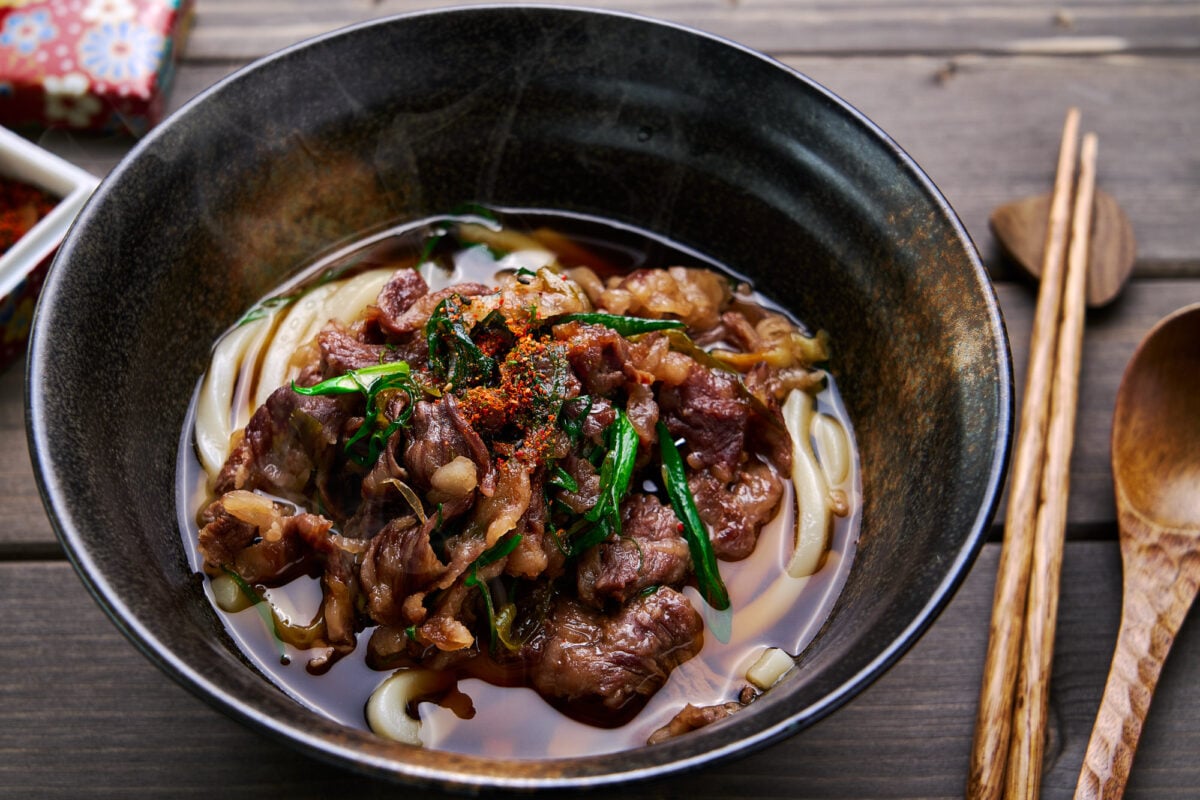 Steamy bowl of udon noodle soup. topped with tender beef and scallions simmered in a savory sweet sauce.