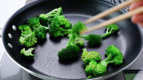 Stir-frying broccoli in frying pan.