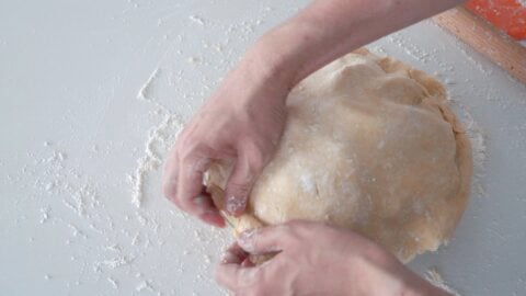 Folding the top crust under the bottom crust of the apple pie.