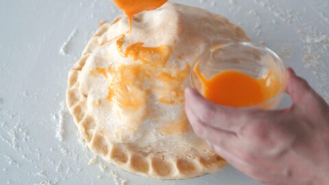 Brushing on an egg wash onto the top crust of a pie.