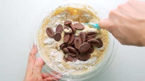 Mixing chocolate chunks into banana bread batter.