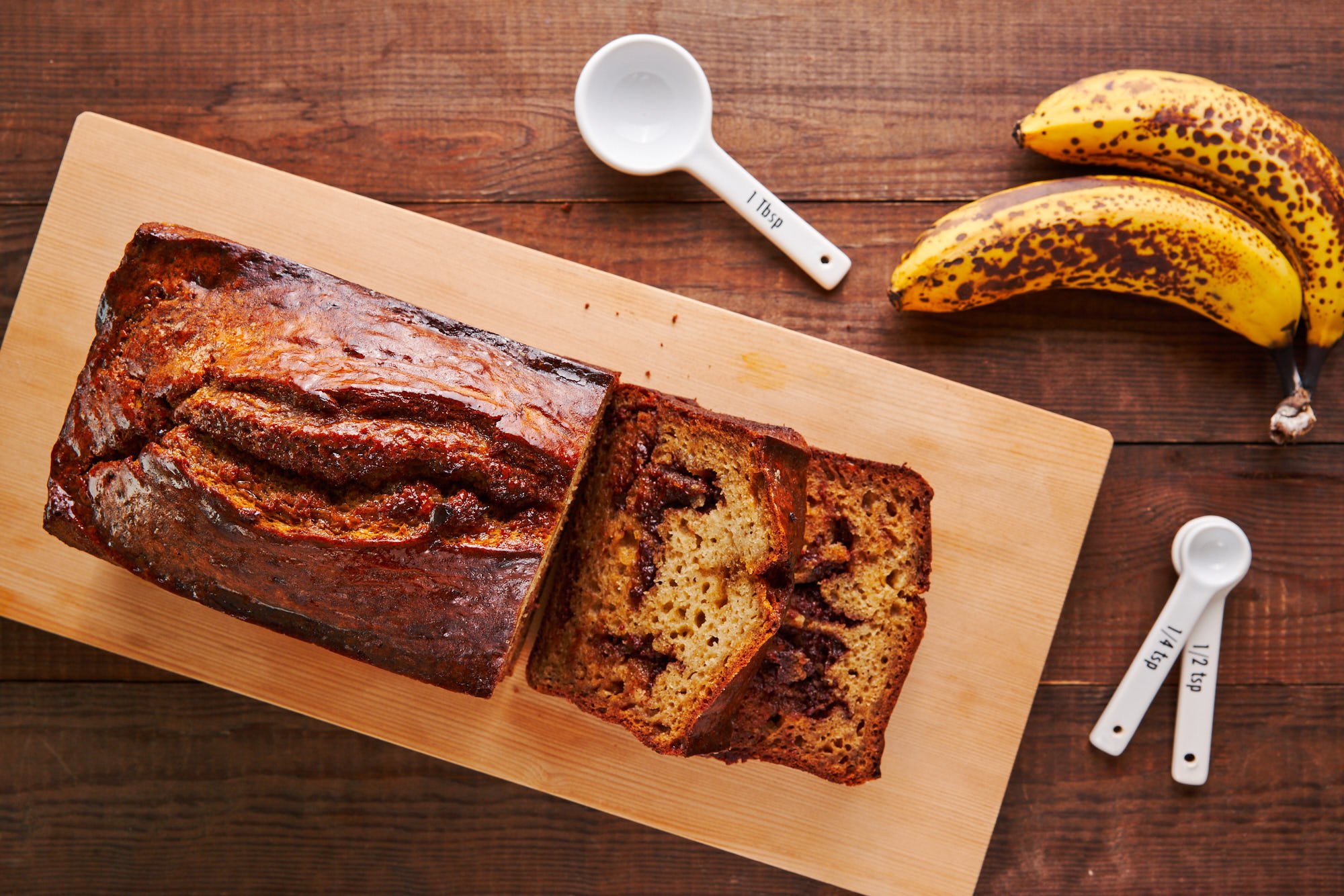 Slices of chocolate chunk banana bread on a wooden cutting board.