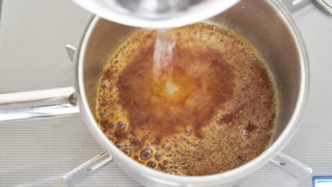 Cooling caramelized sugar with water for making panna cotta.