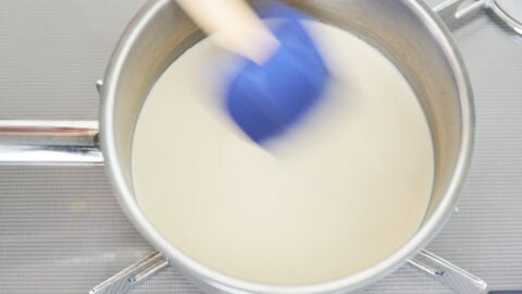 Melting sugar in cream and vanilla in a stainless steel pot for making panna cotta.