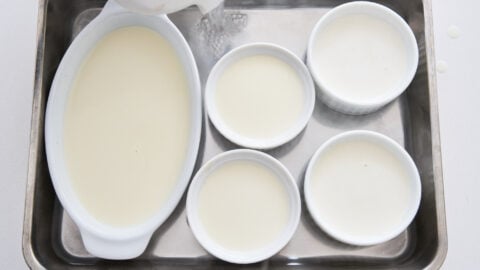 Panna cotta filled ramekins in a hot water bath.