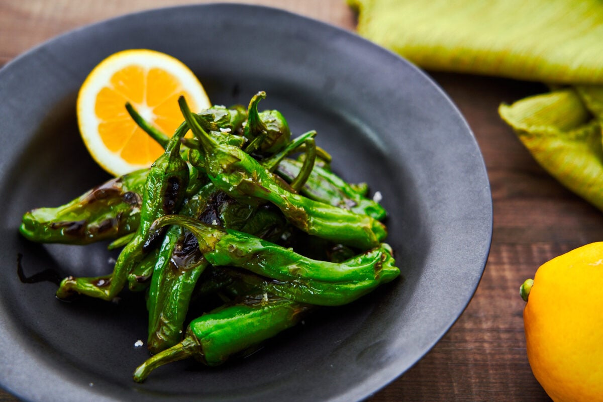 Char-grilled blistered shishito peppers with smoked salt and lemon.