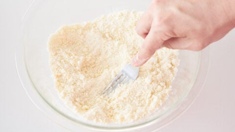 Butter is cut into the flour mixture to make fluffy tender biscuits for blueberry cobbler.