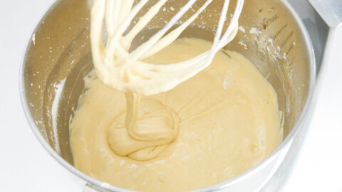 Olive oil cake batter with ribbons of batter falling off the whisk attachment of a stand mixer.