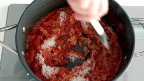 Stirring grated Pecorino Romano cheese into Amatriciana Sauce.