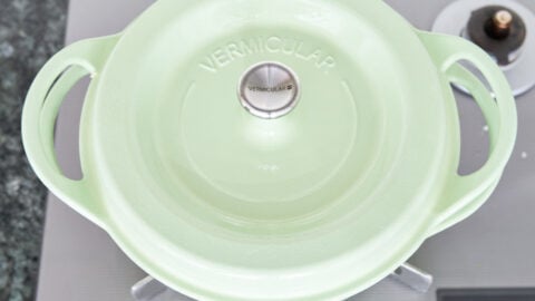 Green dutch oven covered with a lid on a a grey stove.