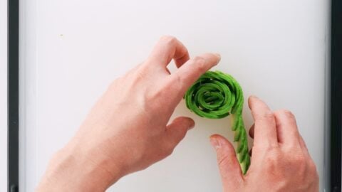 Rolling sliced avocado to make a rose.