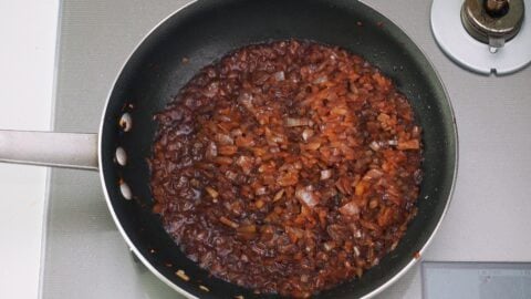 Pan of sauteed onions being deglazed with red wine.