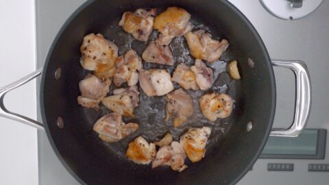 Browning chicken thighs in a frying pan.