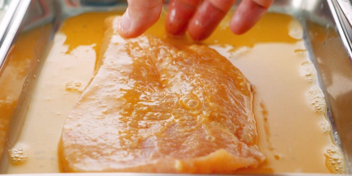 Chicken breast coated in egg before breading.