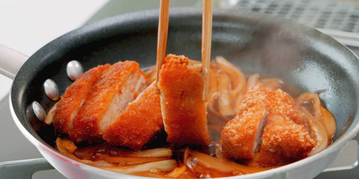 Adding Chicken Katsu to onions and dashi broth for katsudon.