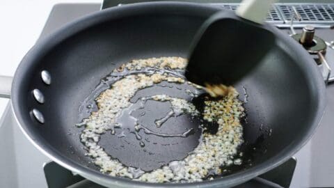 Browning minced garlic in a frying pan with oil.