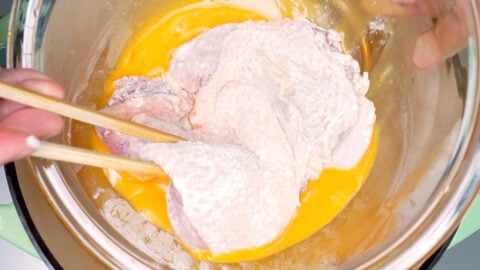 Dipping chicken in egg before frying.