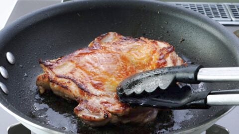 Browning meat-side of chicken in a frying pan.