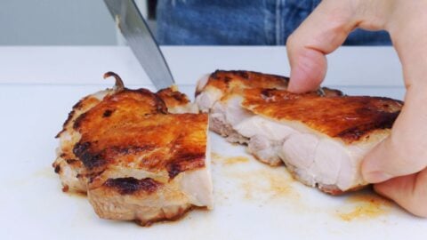 Slicing pan-roasted chicken in half after resting for 10 minutes.