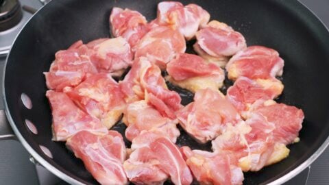 Pan-frying chicken thighs to make chicken teriyaki.