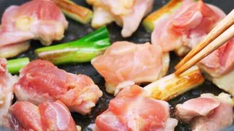 Chicken and scallions grilling in a pan.