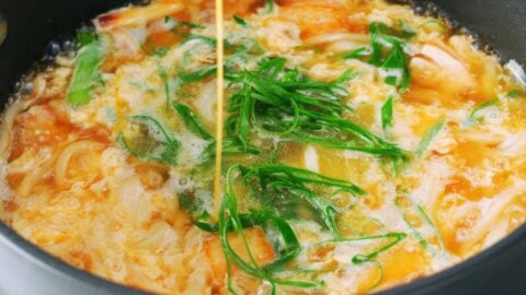 Drizzling egg into chicken udon noodles.