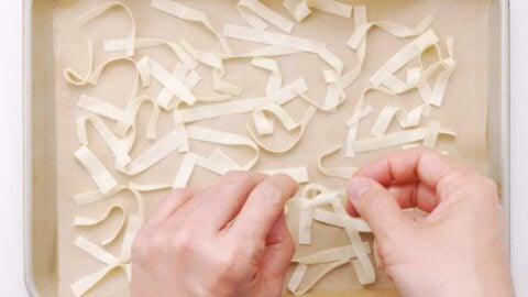 Twisting wonton strips and placing them on a baking sheet.