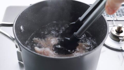 Poaching chicken in a pot of water.