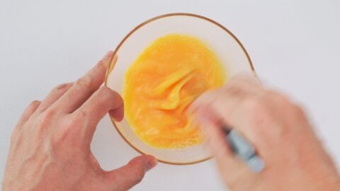 Beating eggs in a bowl with chopsticks.