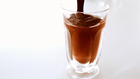 Pouring a plant-based 1-minute chocolate chia pudding into a glass.