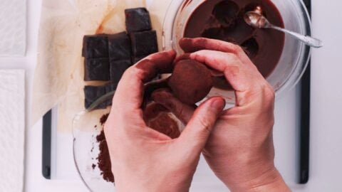 Dusting chocolate mochi balls with cocoa powder.