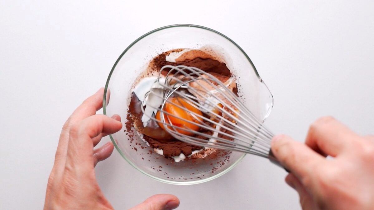 Whisking eggs, cream, cocoa powder, and sugar together to make Chocolate Mug Cake.