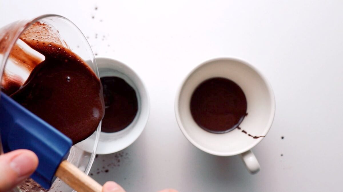 Adding the chocolate batter to oiled mugs.