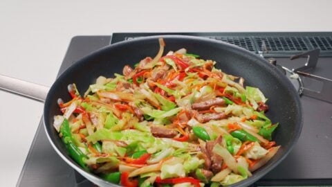 Chop Suey with pork, cabbage, carrots, peppers, snap peas, celery and onions in a frying pan.