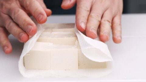 Drying cubes of tofu using paper towels.