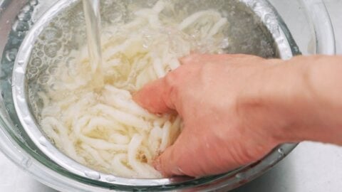 Washing udon noodles to remove extra starch.