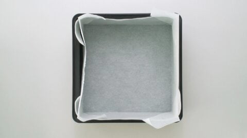 Square baking pan lined with parchment paper for making Datemaki.