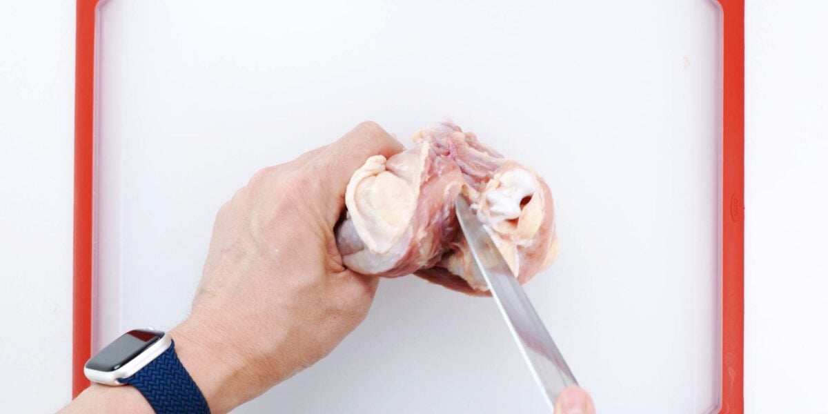 Separate thigh bone from chicken leg.