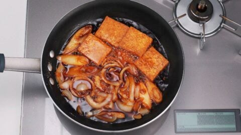 Simmering onions, scallions and tofu in a savory sweet sauce for gyunabe.