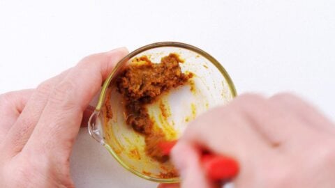 Mixing curry and garlic to make a paste.