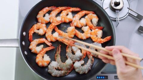 Flipping pan-fried shrimp over.