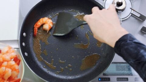 Removing shrimp from frying pan.