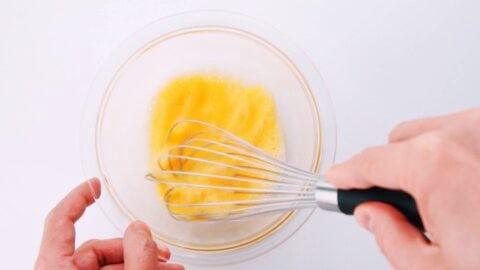 Whisking egg and water together in a glass bowl to make batter for ebi fry.