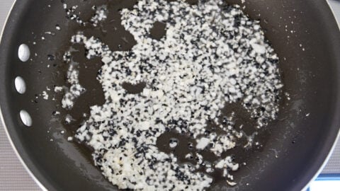 Garlic, ginger, and Nigella seeds frying in a pan for making eggplant curry