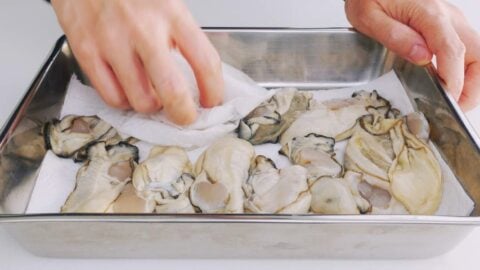 Patting oysters dry with paper towels.