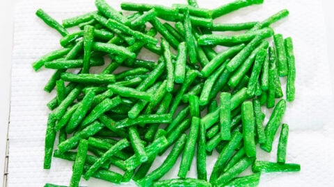 Oil-blanched green beans draining on paper towels before being stir-fried with black bean sauce.